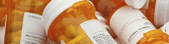 A bunch of bottles of pills are stacked on top of each other.