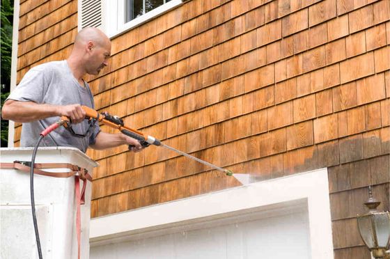 Professional pressure washer cleaning the walls of a houose