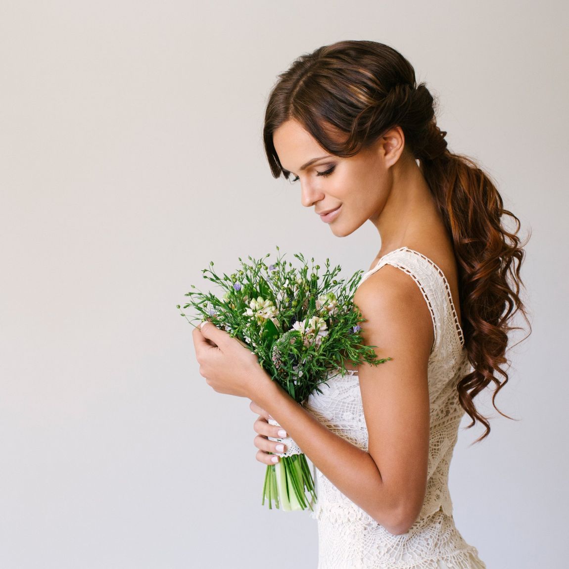 Studio shot of young beautiful bride on light background. Professional make up and hair style.
