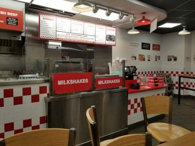 The inside of a fast food restaurant with tables and chairs.