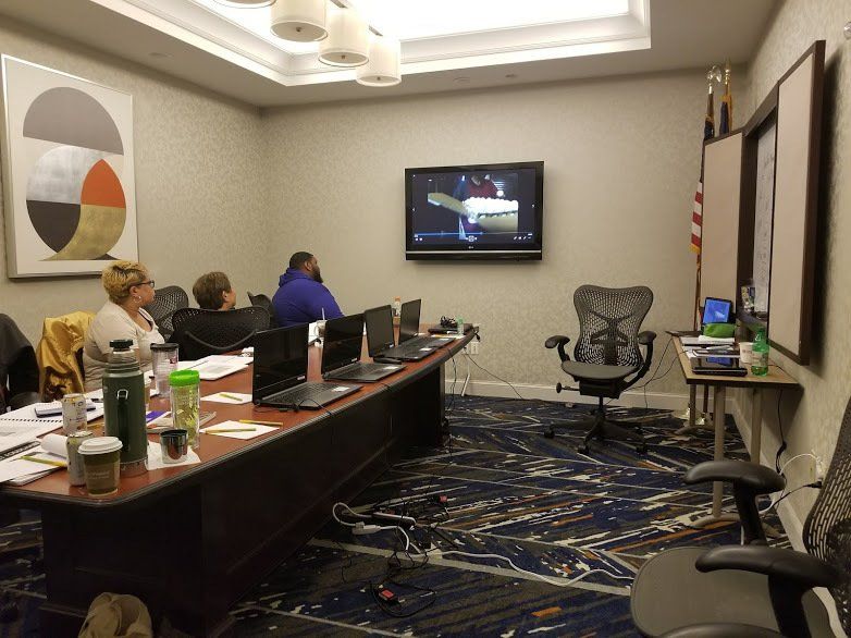 A group of people are sitting at a long table in a conference room.