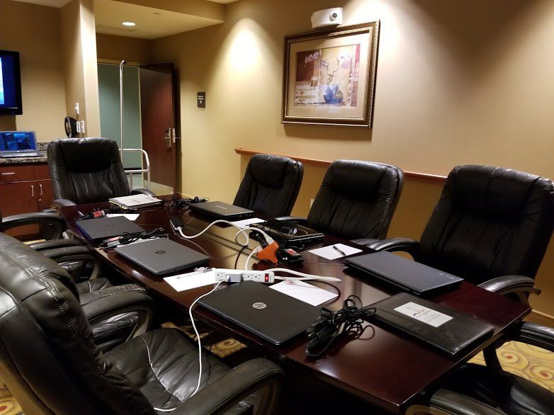 A conference room with a table and chairs and laptops on it
