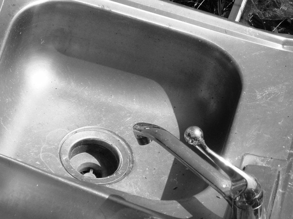 A black and white photo of a kitchen sink with a faucet
