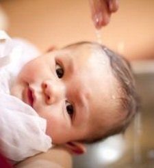 Baby being baptized with water.