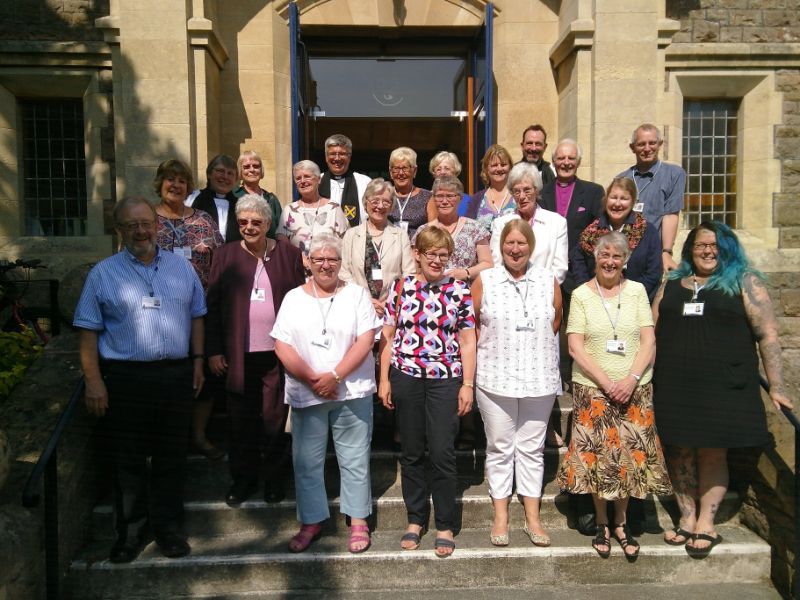 Group of people standing on steps in front of a building with an open doorway.