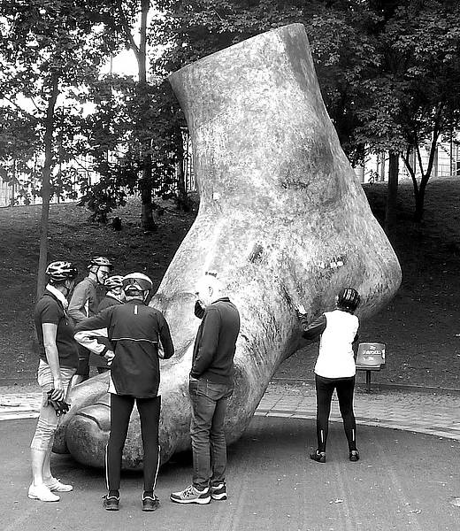 Foto von Tandemfahrern, die um dem riesengroßen Fuß von Uwe Seeler stehen