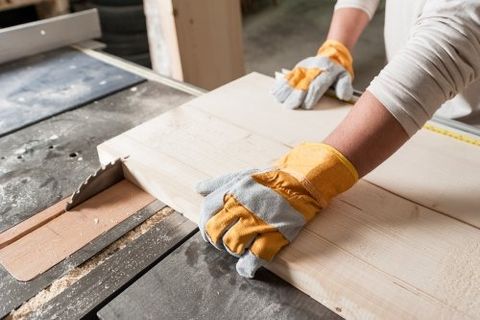 due mani con dei guanti che tengono un asse di legno