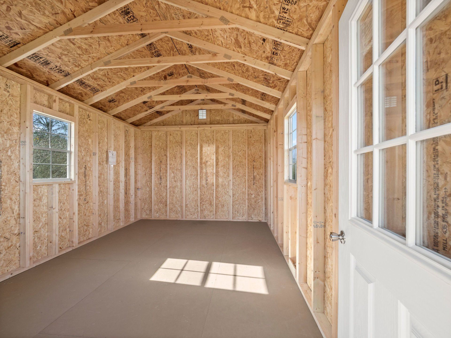 The inside of a wooden shed with a door and windows.