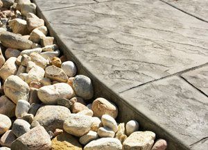 Rocks border textured, gray concrete path.