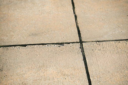 Close-up of concrete pavement with dark sealant in the expansion joints.