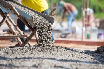 Concrete pouring from a chute onto a construction site.