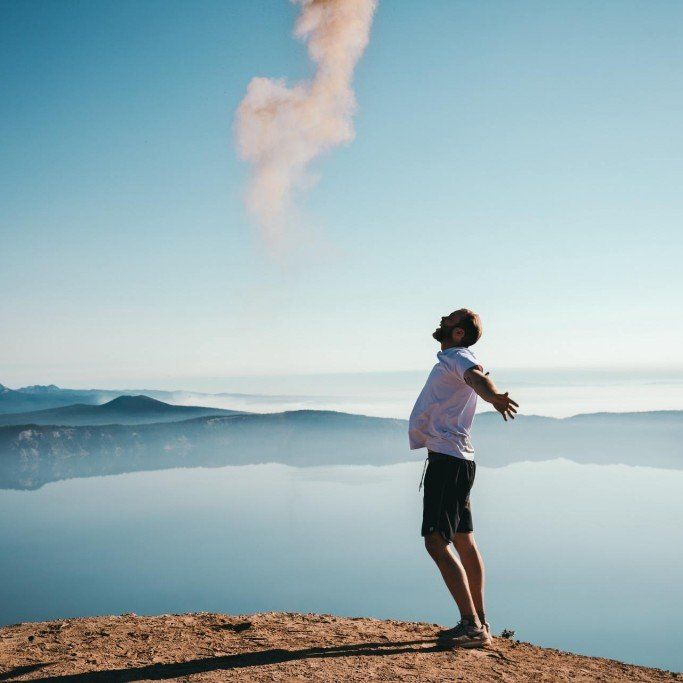 man with arms spread by lake