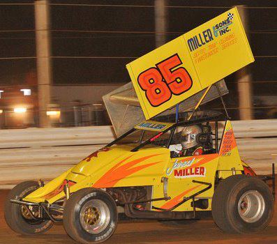 Yellow race car #85 on a track, orange flames, driver in helmet, Miller Sons Inc. logo.