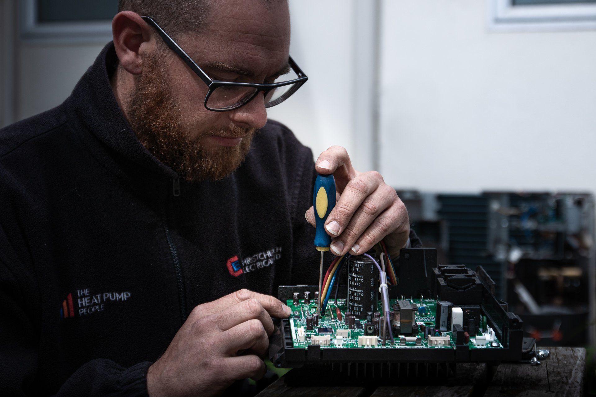 The Heat Pump People technician working on a circuit board.