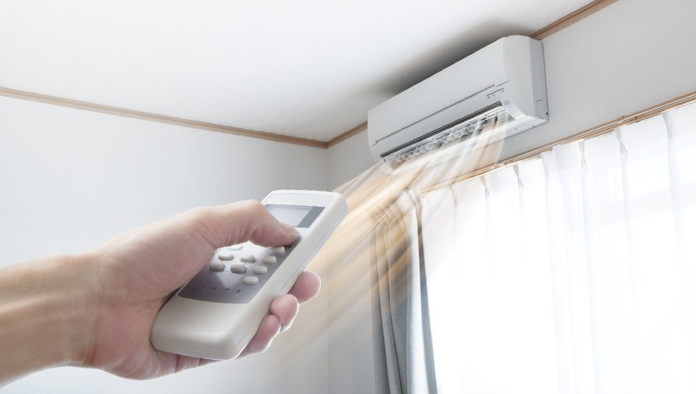 Hand holding heat pump remote control, pointing it at heat pump