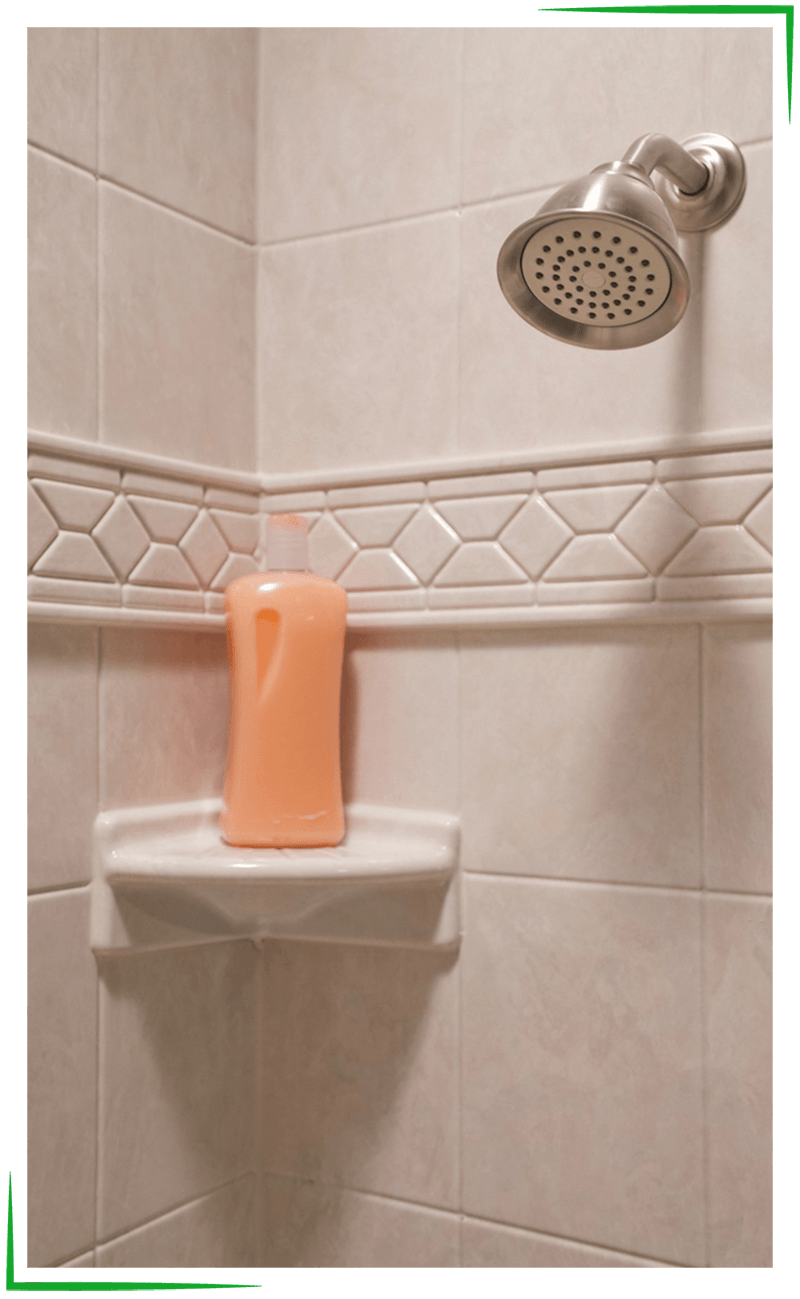 Bath Accessories - Missouri Bath & Window - Springfield, Missouri Corner shower with cream-colored tiles, a decorative tile border, and a built-in soap dish holding an orange bottle.
