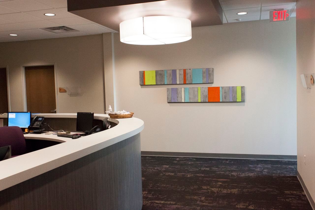 A reception area with paintings on the wall and a red exit sign