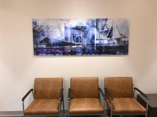 A waiting room with three chairs and a painting on the wall.