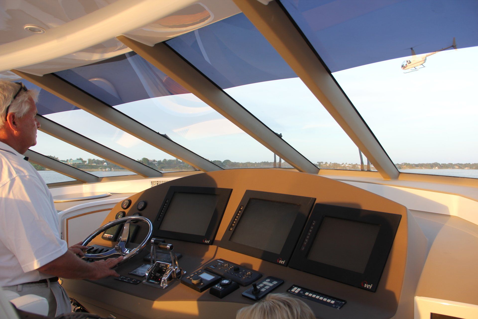 A man is sitting at the steering wheel of a boat