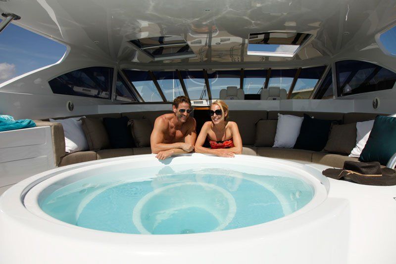 A man and a woman are sitting in a jacuzzi on a boat.