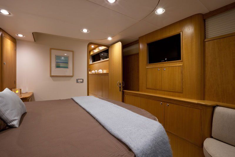 A bedroom on a boat with a large bed and a flat screen tv.