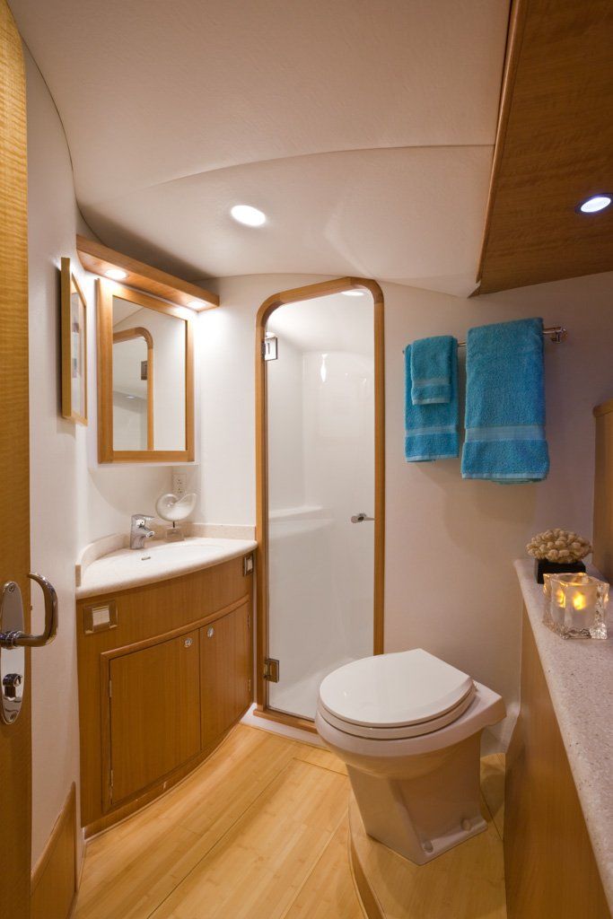 A bathroom on a boat with a toilet , sink and shower.