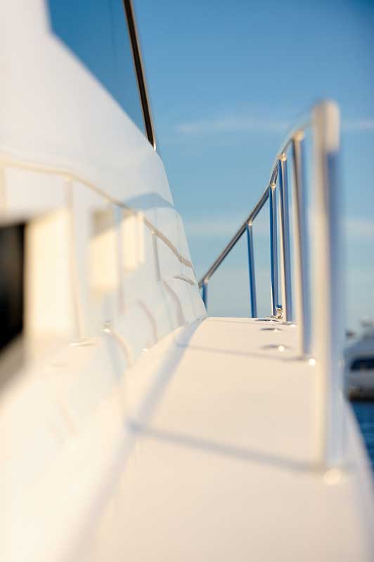 A white boat with a stainless steel railing on the side of it.