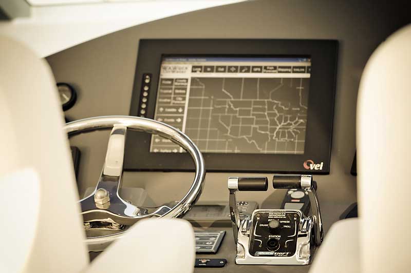 A steering wheel and a monitor on the dashboard of a boat