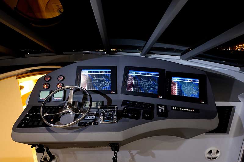 The cockpit of a boat with three monitors and a steering wheel