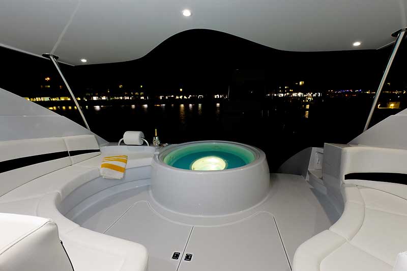 A boat with a jacuzzi on the deck at night