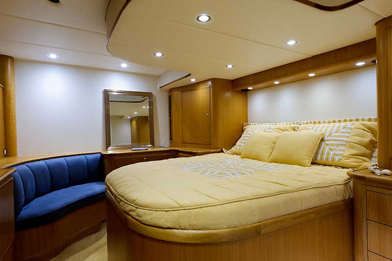 A bedroom on a boat with a large bed and a blue bench.