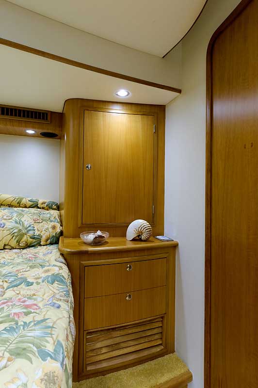 A bedroom on a boat with a bed and dresser.
