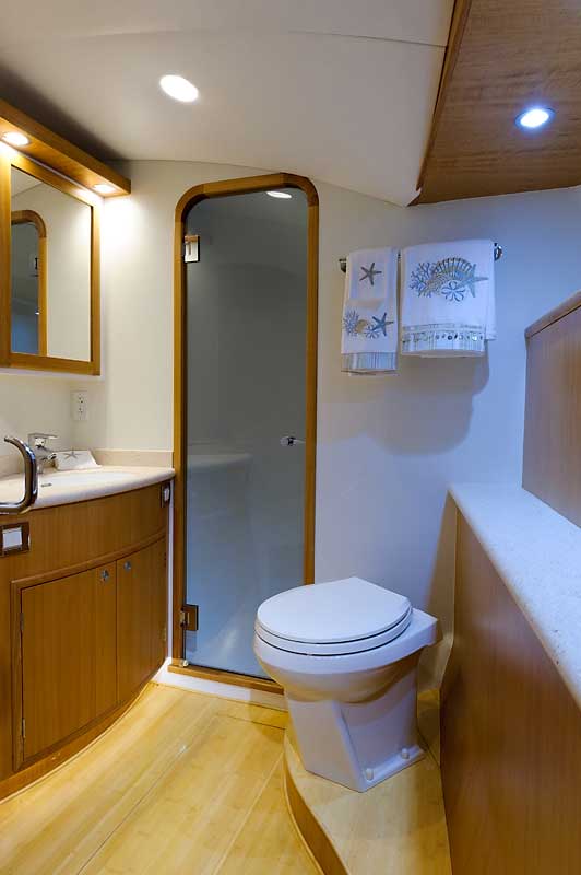 A bathroom on a boat with a toilet , sink and mirror.