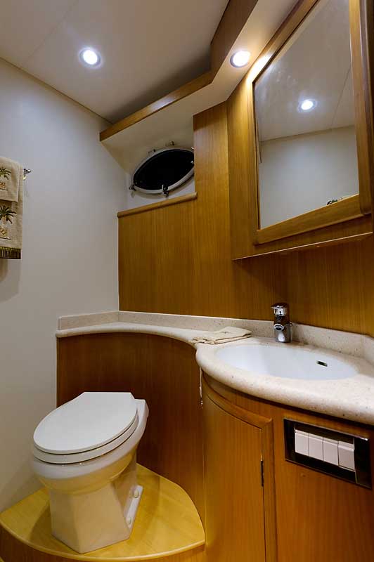 A bathroom on a boat with a toilet , sink and mirror.