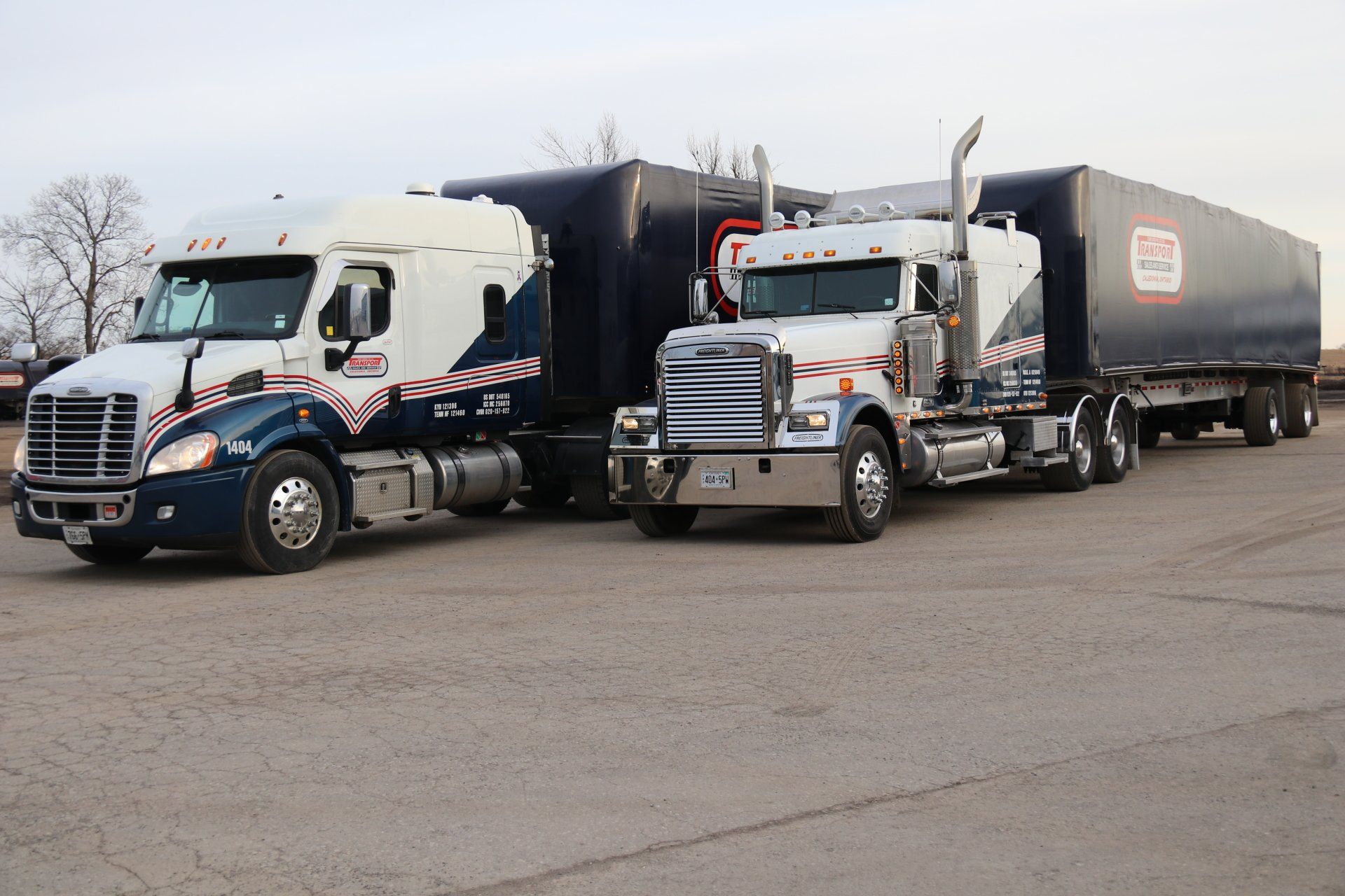 Two semi trucks are parked next to each other in a parking lot.
