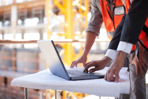 Construction workers using laptop on construction site