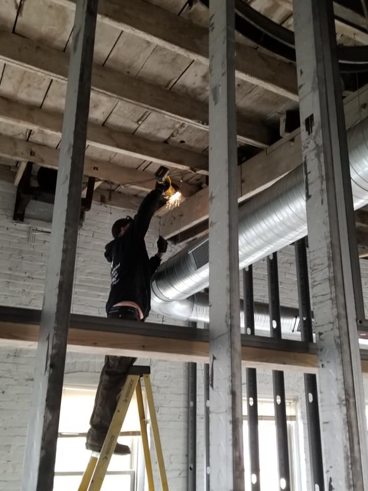 Person welding on a beam inside a building under construction.