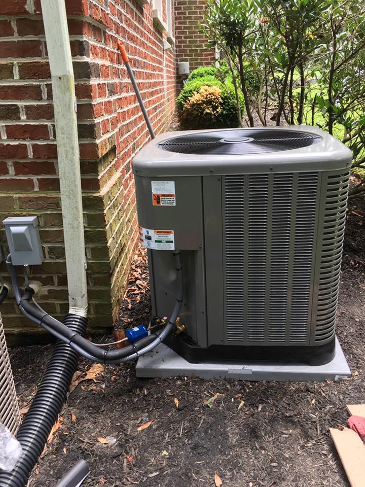 Air conditioning unit next to a brick wall with electrical components.