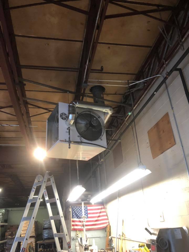 An industrial ceiling-mounted air handling unit, a ladder, and an American flag.