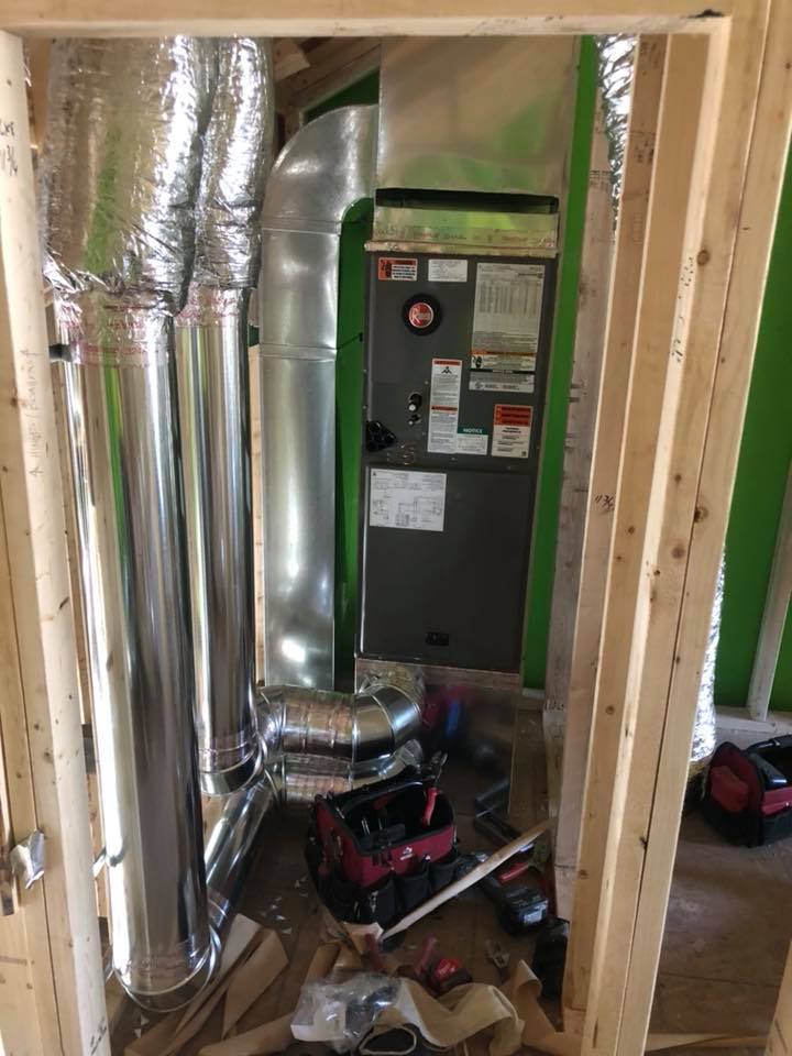 HVAC system installation in a new construction. Furnace with ductwork visible, tools on floor.