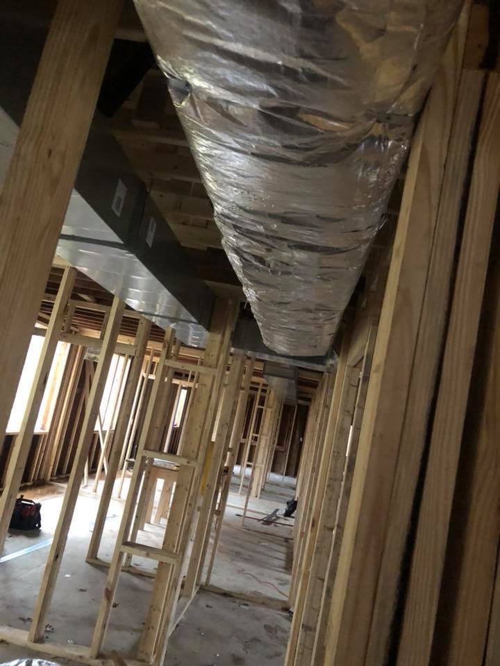 Unfinished building interior with wood framing and ductwork running along the ceiling.