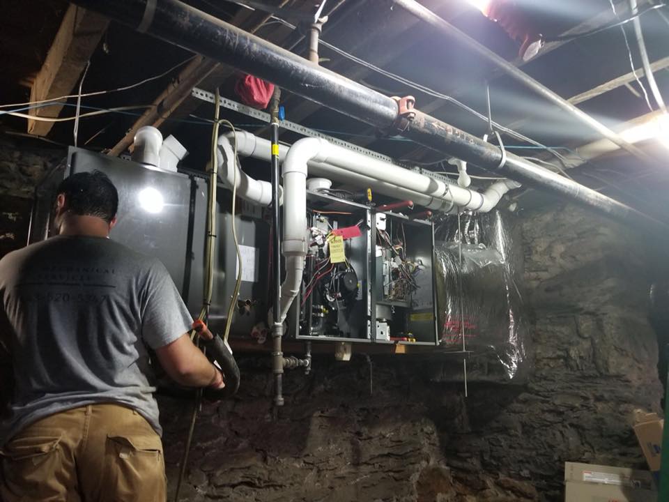 A person working on an HVAC system installed in a basement.