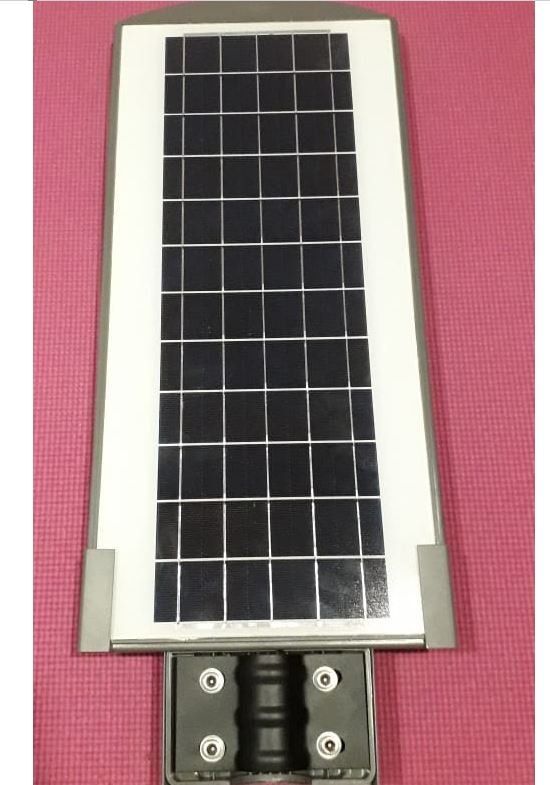 Pequeño panel solar rectangular con marco blanco y celdas oscuras, montado sobre un soporte sobre un fondo rosa.