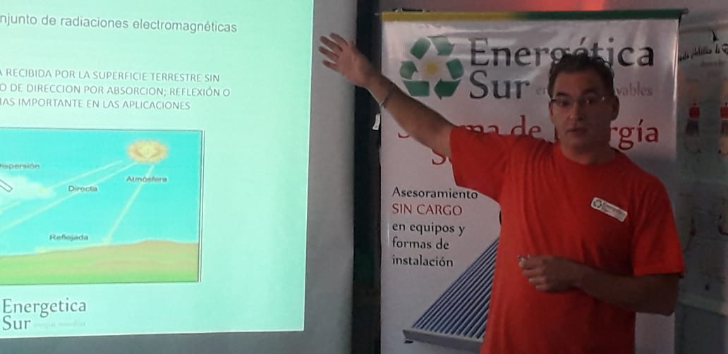 Hombre haciendo una presentación junto a una diapositiva proyectada y una pancarta de Energética Sur en una conferencia.