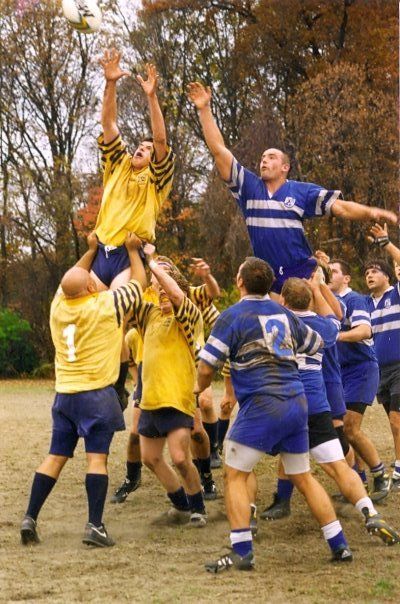 A group of men are playing rugby and one has the number 2 on his jersey