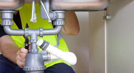 A plumber working underneath a sink