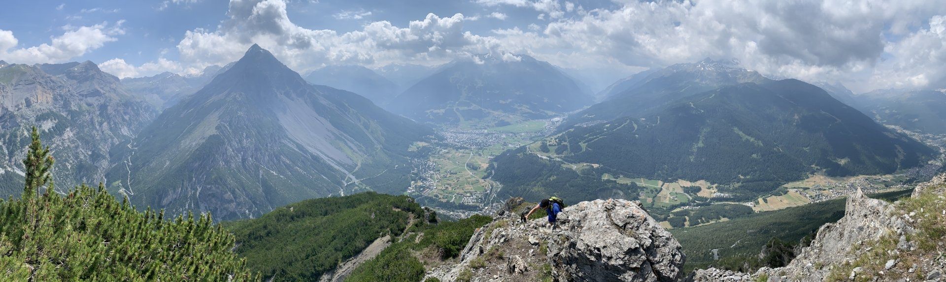 Una persona è in piedi sulla cima di una scogliera rocciosa che domina una catena montuosa.