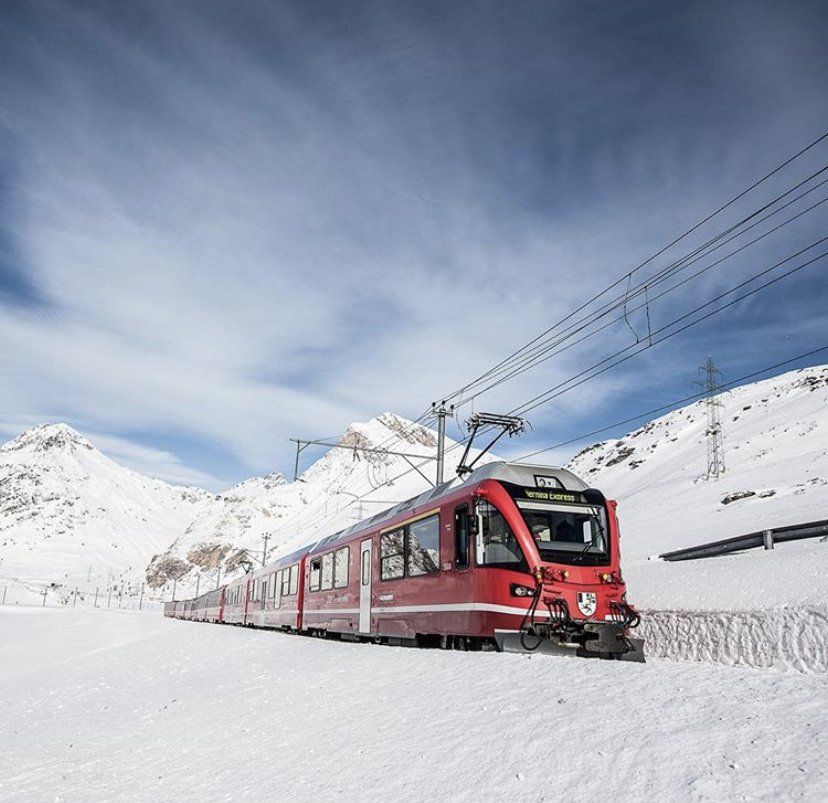 Un treno rosso sta scendendo da una montagna coperta di neve