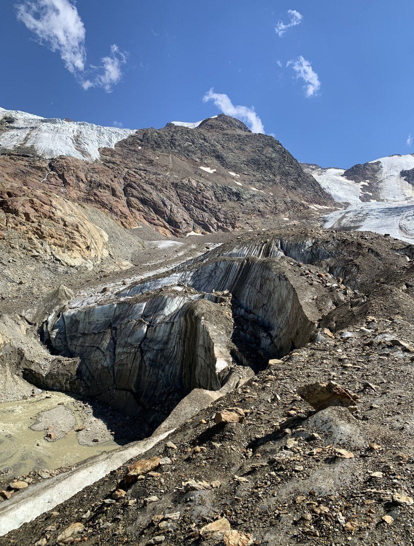 Una grande roccia nel mezzo di una montagna con una montagna sullo sfondo.