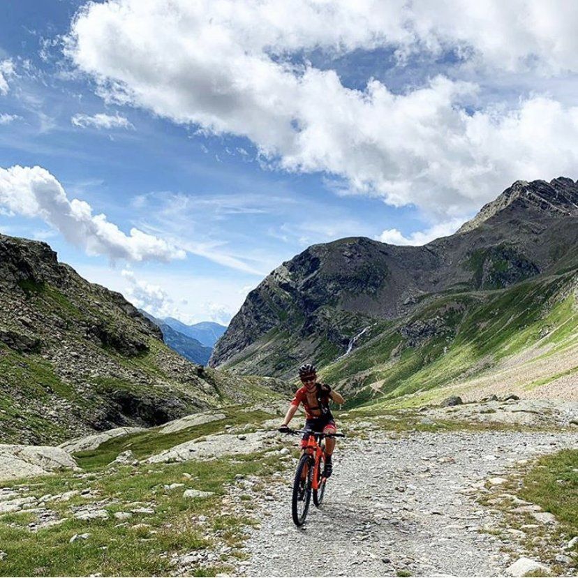 Una persona sta andando in bicicletta su una strada sterrata in montagna.